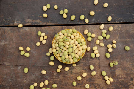 closeup bunch the ripe green yellow soybean in the plastic bowl over out of focus wooden brown background.の写真素材
