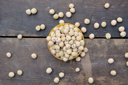 closeup bunch the ripe yellow brown peas beans in the plastic bowl over out of focus wooden brown...