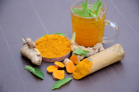 closeup the brown yellow color turmeric with juice and mint over out of focus brown background.の写真素材