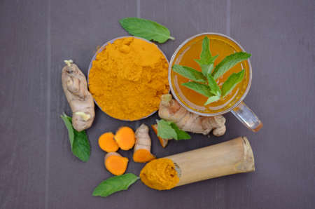 closeup the brown yellow color turmeric with juice and mint over out of focus brown background.の写真素材
