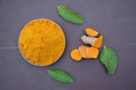 closeup the brown yellow color turmeric with green mint over out of focus brown background.の写真素材