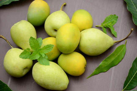 closeup the bunch ripe green pears and yellow mango fruit with leaves over out of focus brown...
