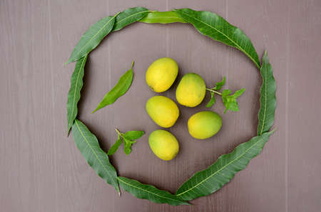 closeup the bunch ripe green yellow mango fruit with green mint and leaves over out of focus brown...
