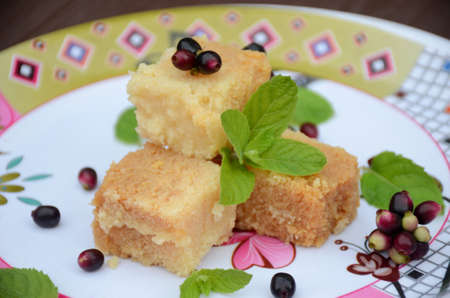 closeup brown color milk cake sweet with black j amble and green mint over out of focus white brown...