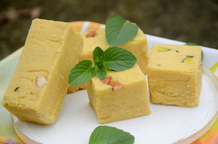 closeup the bunch yellow gram flour sweet with green mint over out of focus white brown background.