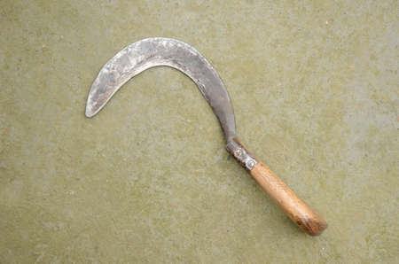 closeup the old paddy cutting curves with handle over out of focus brown background.