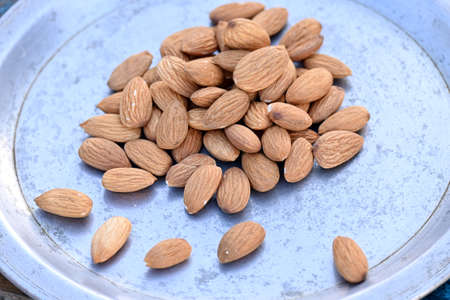 closeup the bunch brown almond nuts over out of focus grey background.の写真素材