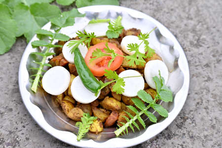 closeup the bunch sliced tomato with white radish and fried veg ,green leaves in the metal plate...