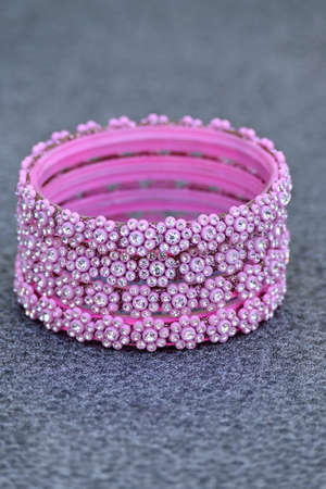 closeup the bunch pink silver bangle over out of focus grey background.