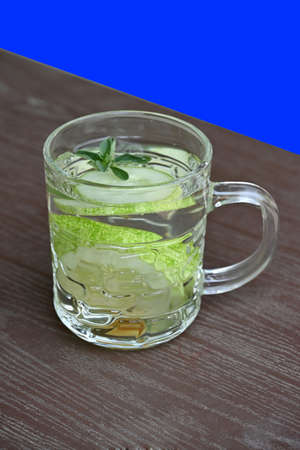 closeup the sliced green ripe cucumber juice in the glass soft focus natural grey blue background.の写真素材