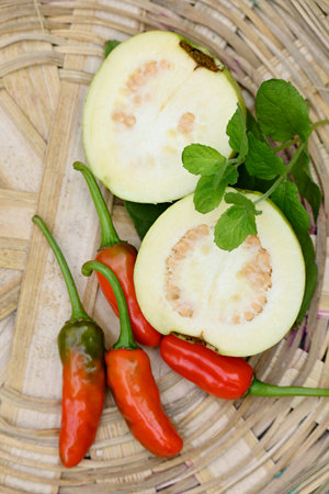 closeup the bunch ripe yellow white guava fruit sliced with red chilly and green leaf in the brown...