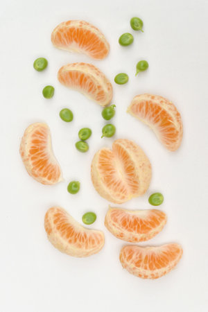 closeup the bunch ripe sliced orange fruit with green peas on the white background.の写真素材