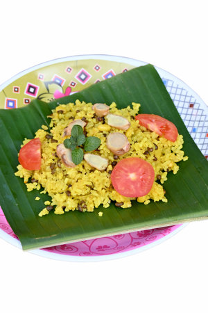closeup the yellow fried rice with red sliced tomato ,brown ginger,green mint,in the banana leaf and...
