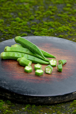 closeup the bunch green lady finger sliced cut piece on the red brown wooden soft focus natural green brown background.の写真素材
