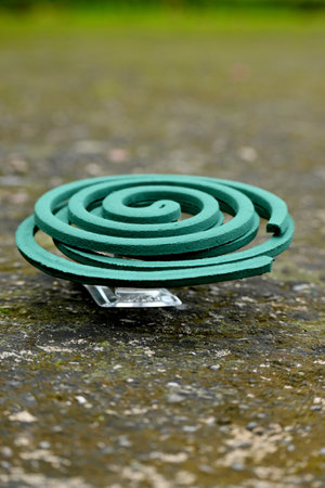 closeup the green mosquito coil hold with metal stand soft focus natural green brown background.の写真素材