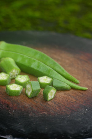 closeup the bunch green lady finger sliced cut piece on the red brown wooden soft focus natural green brown background.の写真素材