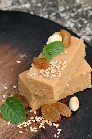 closeup the bunch brown color condensed milk sweet with green mint and pea nut,sesame grain,drilled grapes on the brown wooden soft focus grey brown background.の写真素材