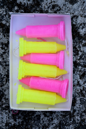 closeup the bunch colorful yellow pink candles in the white paper box on the row soft focus natural grey brown background.の写真素材