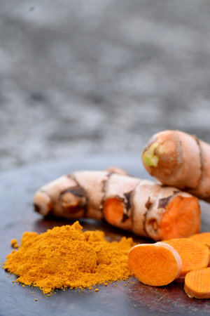 closeup the bunch sliced orange color turmeric with powder on the wooden soft focus natural grey brown background.の写真素材