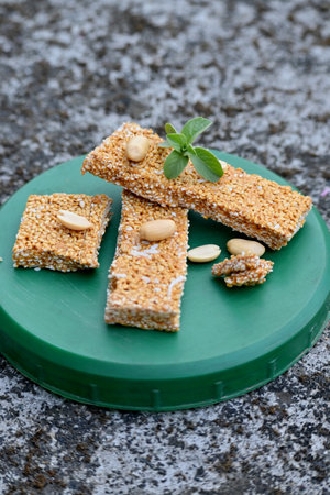 closeup the bunch sesame with dark sugar sweat and pea nut seeds ,green mint on the green plastic box soft focus natural grey brown background.の写真素材