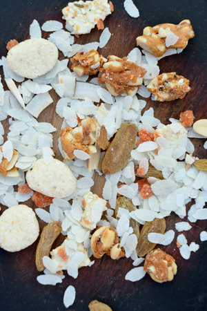 closeup the mix snack food drilled rice coconut,raisins,peanut ,sesame seeds in the wooden on the grey brown background.の写真素材