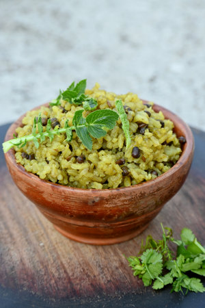 closeup the yellow fried rice with black month,brown ginger,green radish leaves in the wooden bowl soft focus natural grey brown background.の写真素材