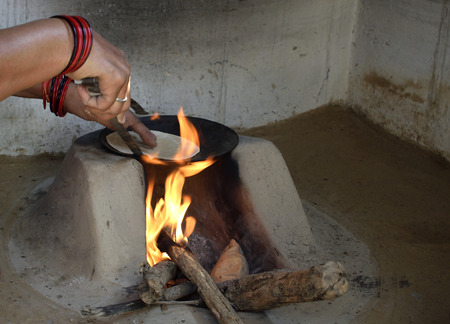 A rural indian woman preparing chapati in traditional way on a wood fired ovenの写真素材