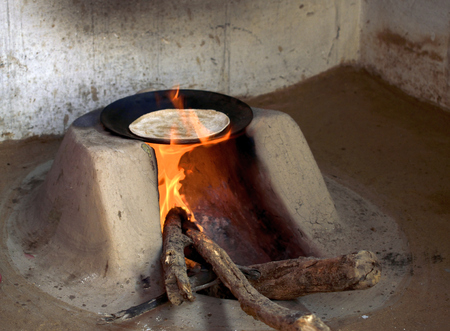 a typical wood fired oven or chulha used to cook food in rural india with a chapati on itの写真素材