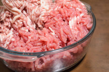 Minced meat in a glass bowl on wooden boardの写真素材