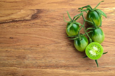 Fresh grape green tomatoes for use as cooking ingredients with a halved tomato in the foreground with copyspace. Top viewの写真素材