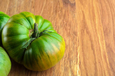 Unripe tomato on a wooden board, copyspace. Agriculture, Gardening, Harvest Concept.の写真素材