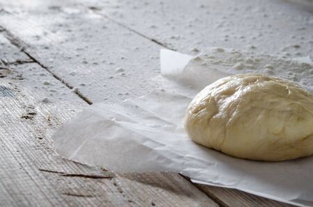 Ball of pizza dough on a rustic wooden background with dusting of flourの写真素材