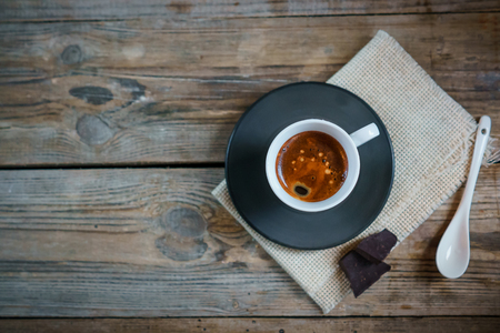 White cup of espresso macchiato with black saucer, stack of dark chocolate bar on old wooden table. View from above.  Cup of Espresso - stock photo.の写真素材
