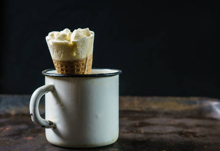 Vintage metallic cup with Ice cream in a waffle Cone on a dark, textured metal surface. Copy space.の写真素材