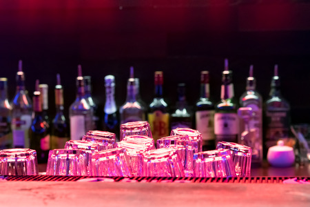 The wooden bar in the restaurant, a bottle of alcohol, soft lights.