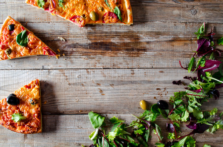 Homemade pizza with salami, olive and fresh herbs lifted sliceの写真素材