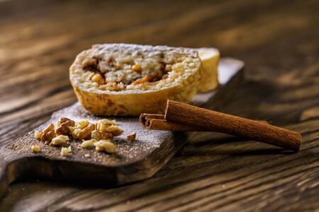 Apple strudel with nuts on a wooden board with a cinnamon stick.の写真素材