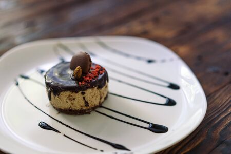 Presentation of dessert on a white plate drizzled with chocolate topping. Background of aged wood.の写真素材
