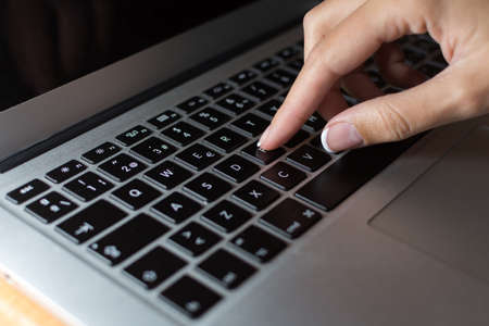 Woman's hand typing on laptop computer keyboardの写真素材