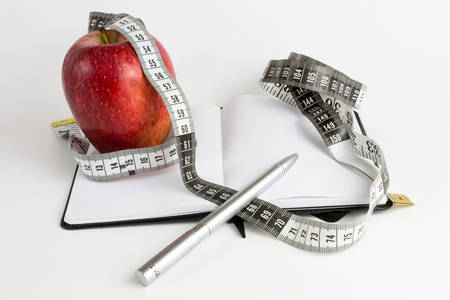 Apple, measuring tape and notebook with white backgroundの写真素材