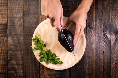 Women's hands cutting an avocado in half. Healthy and vegetarian food.の写真素材