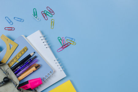 stationery in a small school bag with a plain blue background