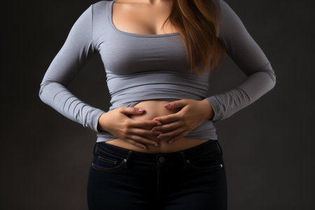 Closeup of a pregnant woman touching her belly on a dark backgroundの素材