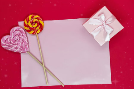 Flat lay background for valentine's day. Sweet lollipops and gift box on red and white background.の写真素材