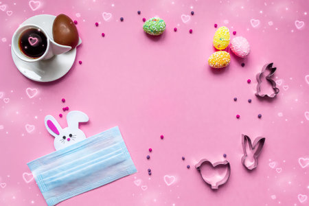 Easter flat lay with a medical face mask, colorful eggs, coffee and handmade cookies, a bunny hiding behind a mask. Holiday concept during the  epidemic and quarantine.の写真素材