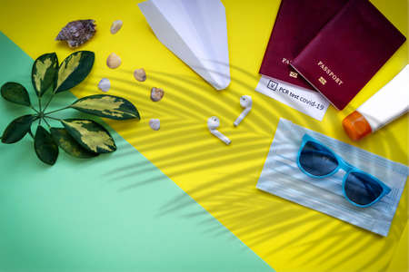 Top view of accessories for a flying holiday. Travel during the virus pandemic. Yellow and green...