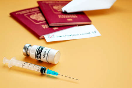 Travel concept during the pandemic. Vaccine and tourist passport on orange background.