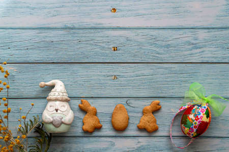 Flat lay easter composition with place for your text on blue wooden background. Homemade cookies in the shape of a bunny, brightly colored eggs. Top View.の写真素材