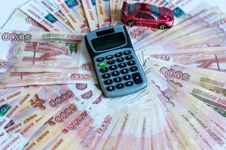 Car purchase planning. Background from banknotes rubles in denominations of five thousand with a calculator and a toy car.の写真素材