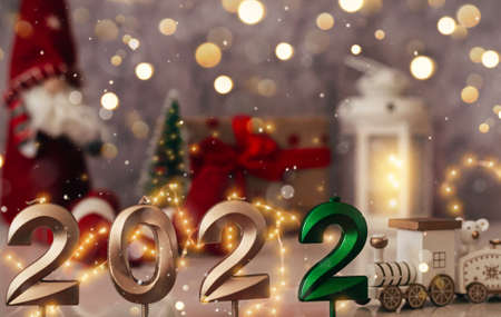 Festive Christmas composition with golden numbers 2022 and sparkles. Santa claus, burning lantern...